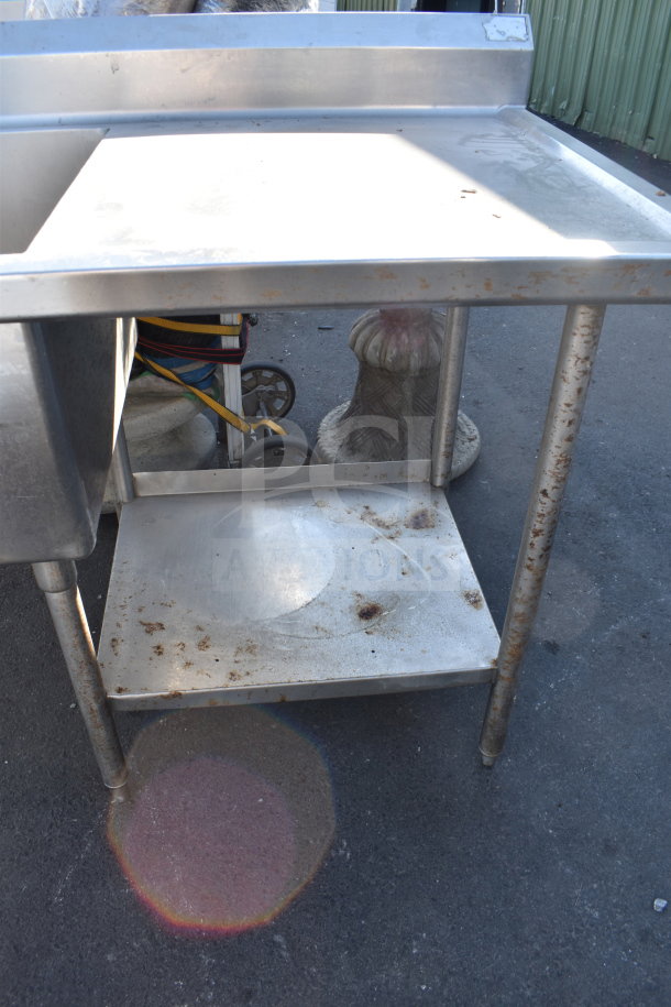 Commercial 2 Bay Sink with Dual Drain Boards, stainless steel, showing signs of rust and wear, on outdoor surface.