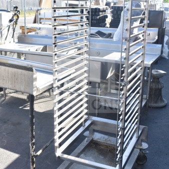 Commercial pan transport rack on casters, compatible with roll-in ovens. Sturdy metal frame, visible wear on wheels.