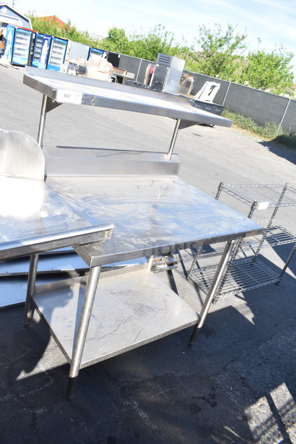 Stainless steel commercial table with over and under shelves, sturdy legs, minor scratches shown, ideal for kitchen use.
