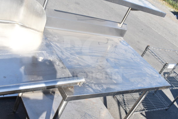 Stainless steel commercial table with over and under shelf, showing light wear and surface marks, ideal for kitchen use.