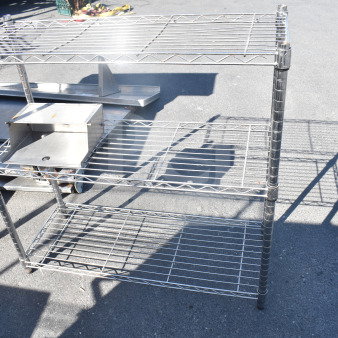 Chrome finish 3-tier wire shelving unit on pavement. In good condition. Buyer must dismantle; consider freight charges.