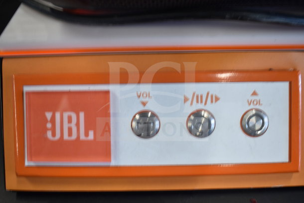 JBL PartyBox speaker control panel with volume and playback buttons, and visible JBL logo.