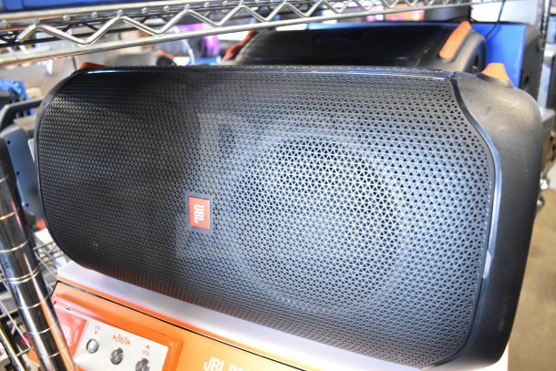 2 JBL PartyBox portable Bluetooth speakers, black mesh grille, visible JBL logo, displayed on a shelf.