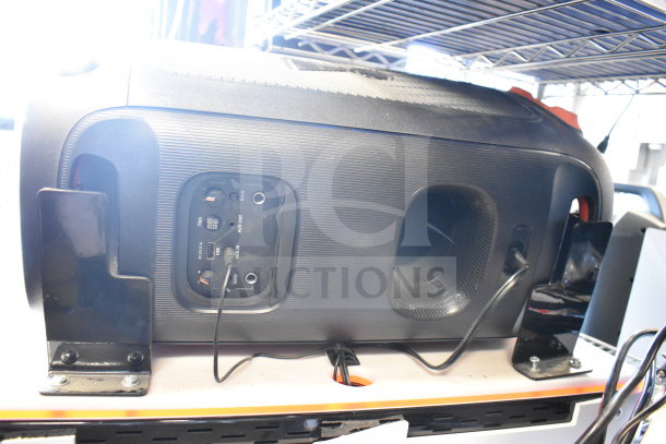 Two JBL PartyBox portable Bluetooth speakers, visible ports, robust build, mounted on a shelf.
