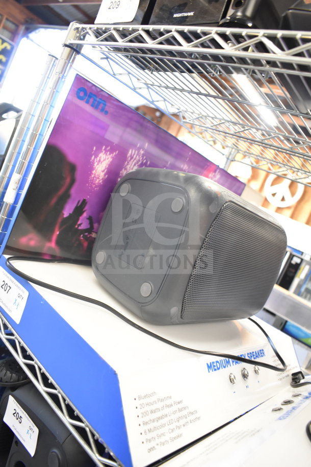 Two Onn portable Bluetooth speakers on metal shelf. Features include 20 hours playtime, 200W peak power, LED effects.