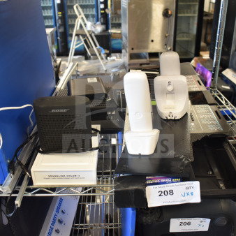 8-item set including Bose SoundLink Color II speaker and Netgear router, displayed on metal shelves. Condition appears used.