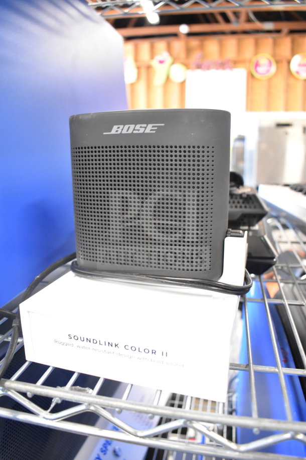 Bose SoundLink Color II speaker on shelf, compact design, black, includes original box displaying product features.