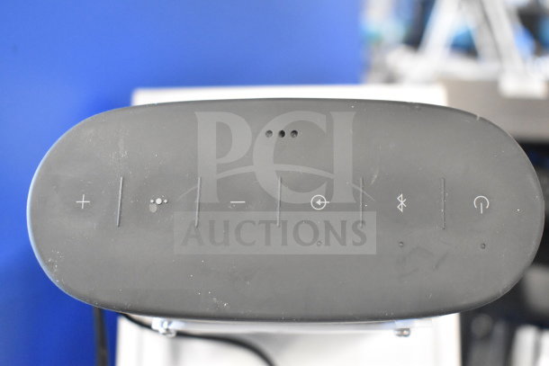 Bose speaker top view showing control buttons, featuring volume, Bluetooth, and power. Black color, used condition.