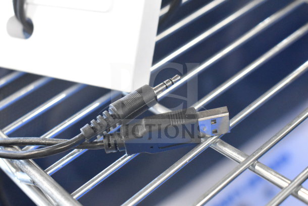 A black USB and 3.5mm audio cable on a metal shelf, part of an auction lot including Bose speaker and Netgear router.