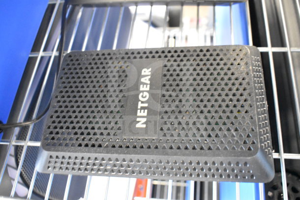 Netgear router on a metal shelf, showcasing its vented black design and clearly visible brand label.