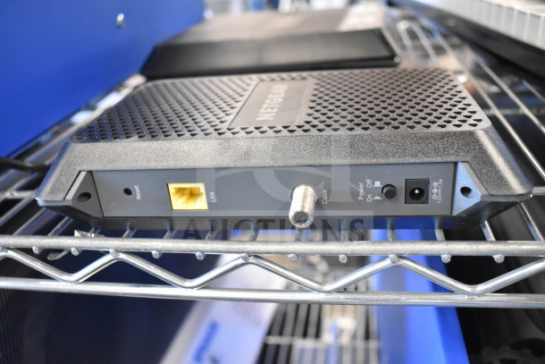 Netgear router on metal shelf, featuring LAN port, cable input, and power switch. Part of 8-item auction bundle.