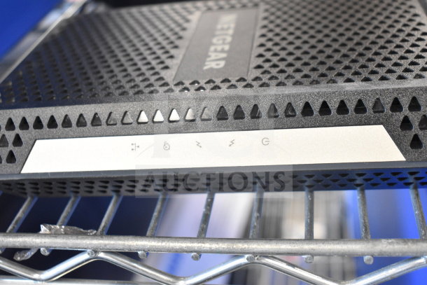 Netgear router on metal shelf, showcasing ventilation holes and status icons; part of an 8-item auction including a Bose speaker.