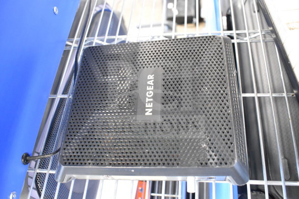 Netgear router with a textured design, visible logo, on metal shelf. Part of a bundle including Bose speaker.