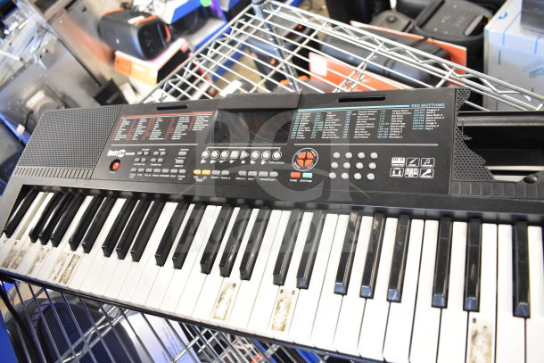 Keyboard with multiple controls and display on a metal shelf, showcasing wear. Background includes Bose and Netgear items.