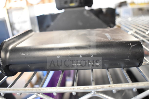 Netgear Nighthawk router, black, visible scuffs, power and connectivity icons on front. Part of 6-item auction lot.