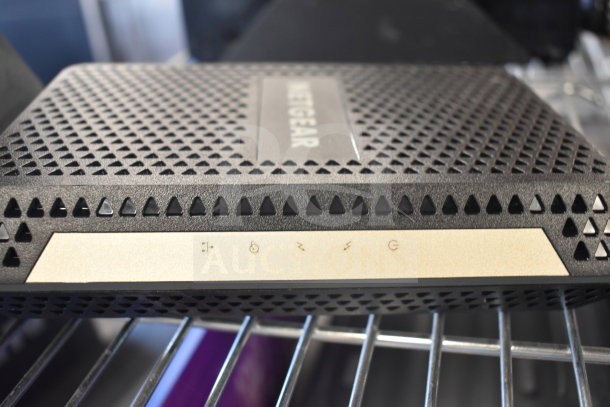 Netgear Nighthawk router, black with perforated design, gold panel indicating connectivity icons, good condition.