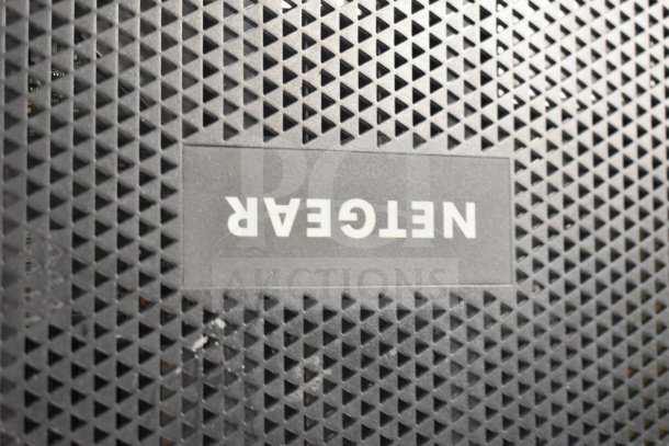 Netgear router with textured black surface, visible logo, part of a 6-item auction lot including a Nighthawk model.