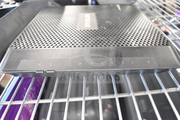 Netgear Nighthawk router, black, on a shelf. Features triangle vent pattern, labeled indicators, in good condition.