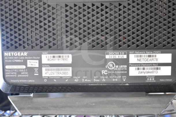 Netgear AC1900 WiFi Cable Modem Router C7000v2, refurbished, with labels showing default access details and serial number.