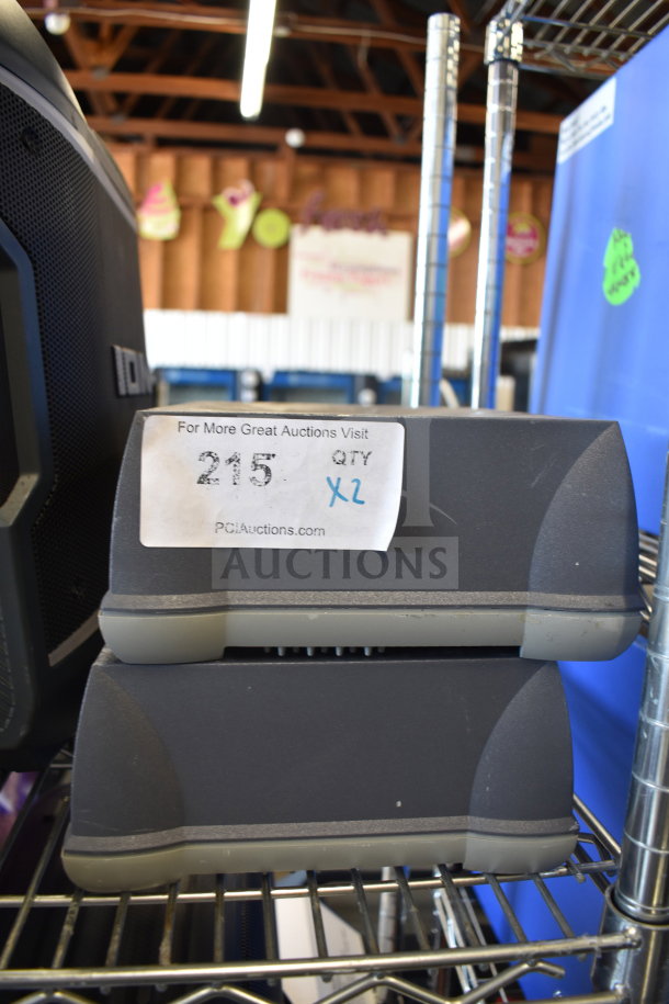 Two Sensormatic ZBAMB9010-IPS deactivator controllers on a metal shelf, auction tag marked "215 QTY x2."