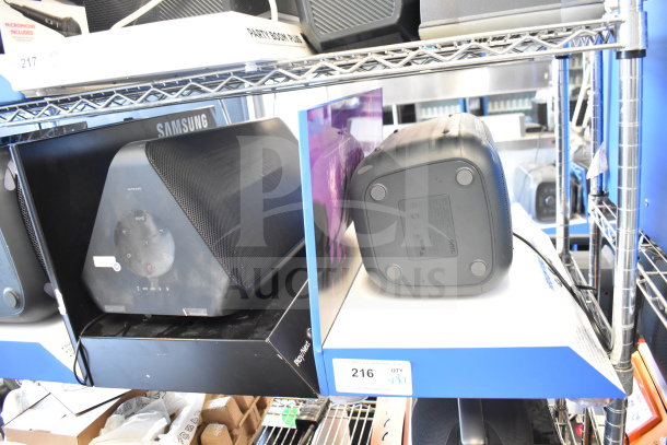 Samsung and Onn speakers, good condition. Samsung has control panel, Onn is a medium party speaker. Auction tag reads "216."
