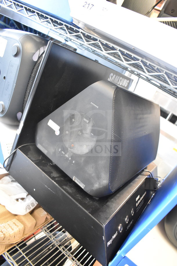 Samsung speaker and Onn medium party speaker on shelf; Samsung branded, visible buttons; good condition.