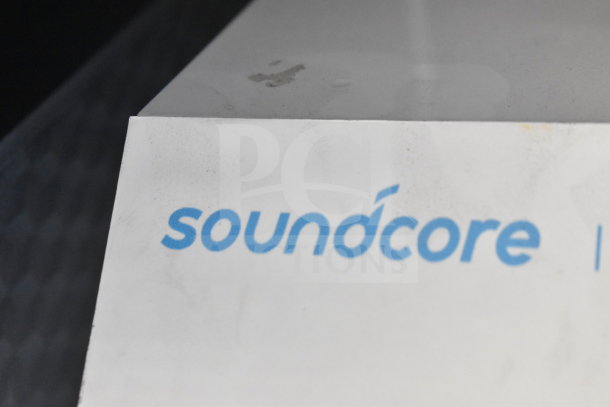 "Soundcore logo on a slightly worn white surface, indicating Anker Soundcore Rave+ Partycast Speaker."