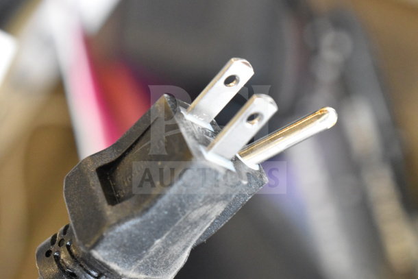Close-up of a store display's power plug, highlighting its prongs and black casing, part of a system with two speakers.