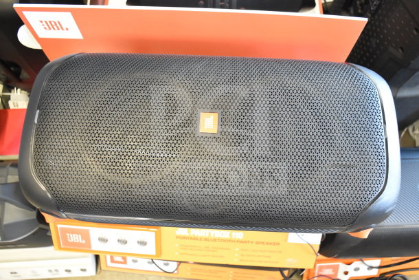JBL PartyBox 110 portable Bluetooth speaker, black, on a retail display shelf. Includes mic/guitar inputs, dynamic light show.