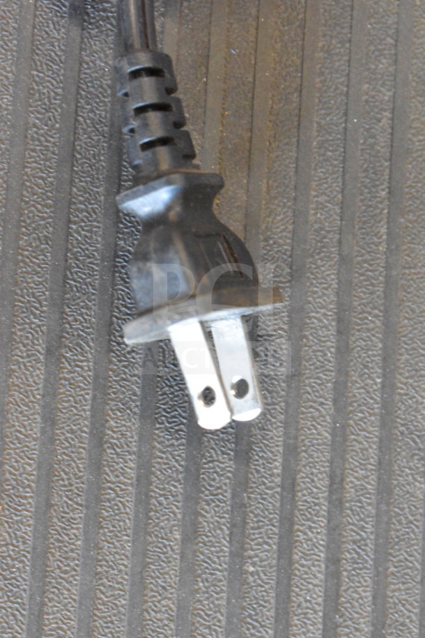 Close-up of a power plug for the Monster MNRRX Rockin' Roller Speaker on a textured surface.