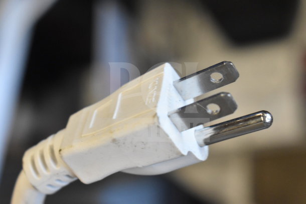 Close-up of a white power plug connected to the Ion Pro Glow 1500 Speaker store display, showing prongs and slight wear.