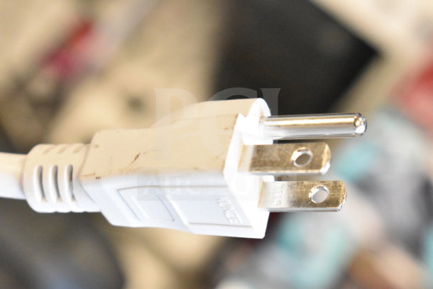 A close-up of a white power plug with visible prongs and slight scuff marks, possibly for a speaker device.