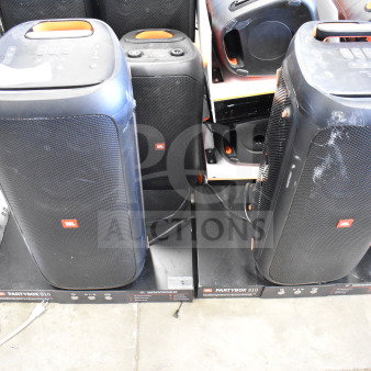 Two JBL Partybox 310 speakers on store display, visible wear, cables connected, marked boxes below each speaker.