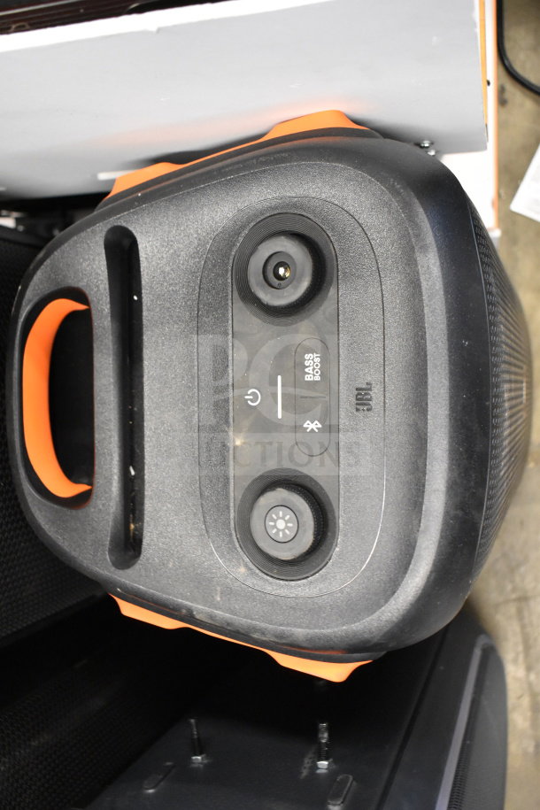 JBL speaker with orange accents, top control panel showing power, bass boost, Bluetooth. Durable design, likely used.