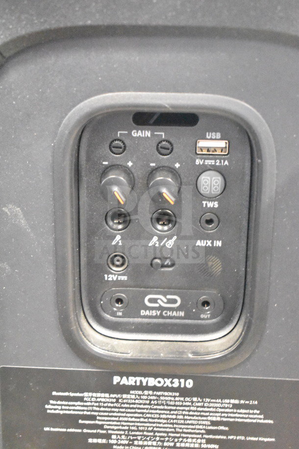 JBL Partybox 310 control panel showing gain knobs, USB port, aux input, and daisy chain options. Model label visible.
