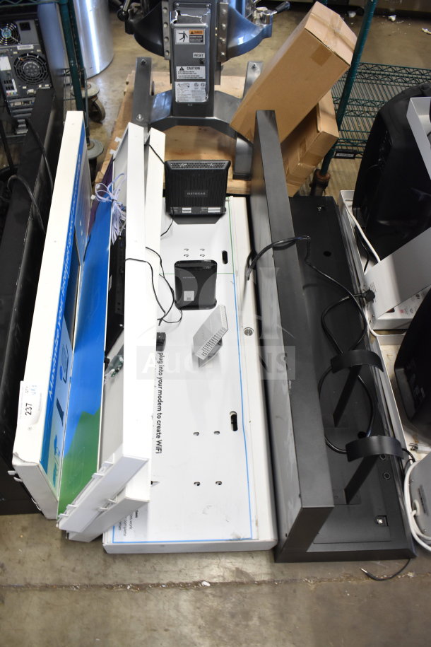 Store display units for auction, featuring NETGEAR Wi-Fi devices. Includes assorted items and cables. Varied conditions.