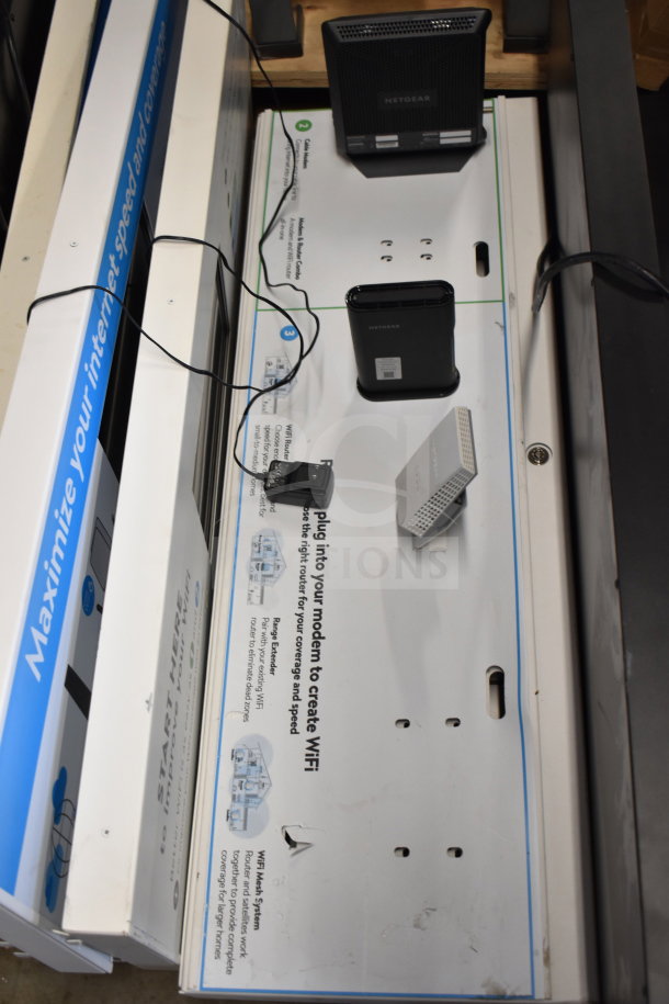 Store display with multiple Netgear routers and modems. Includes informational graphics on WiFi coverage and speed.