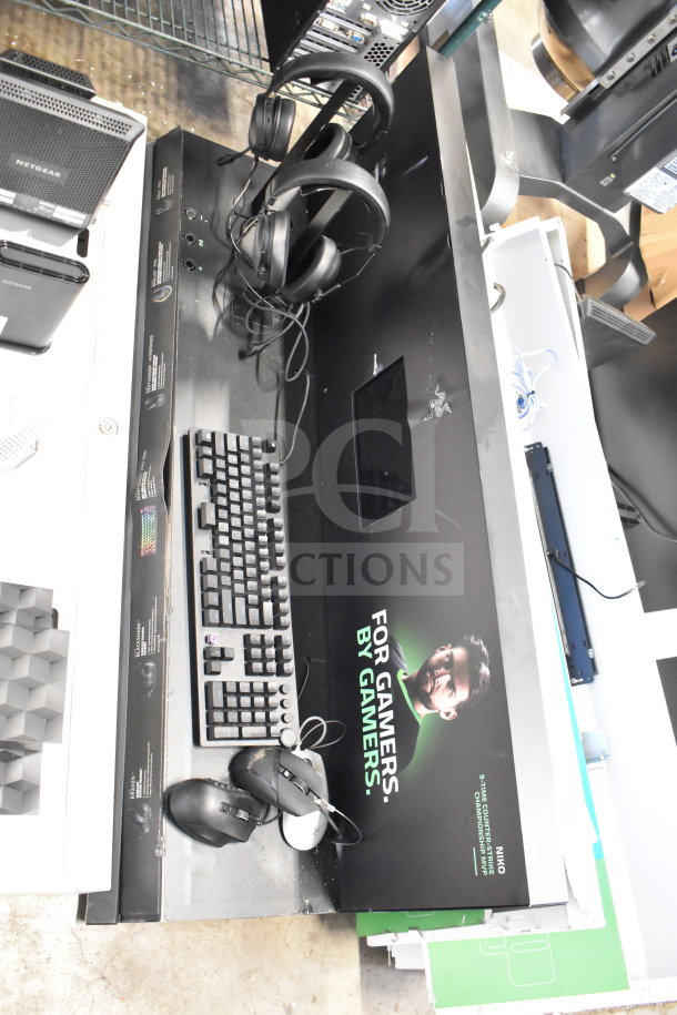 Store display featuring Razer headphones, keyboard, and mouse. Includes Netgear router. Good condition. Marketing text visible.