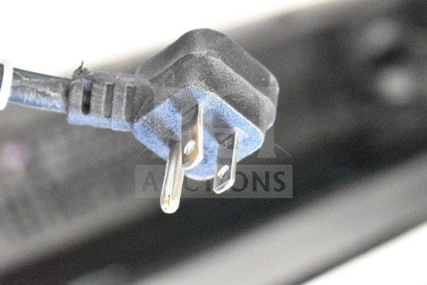 Close-up of a two-prong electrical plug with a blue and black casing, indicating the power connection for auction electronics.