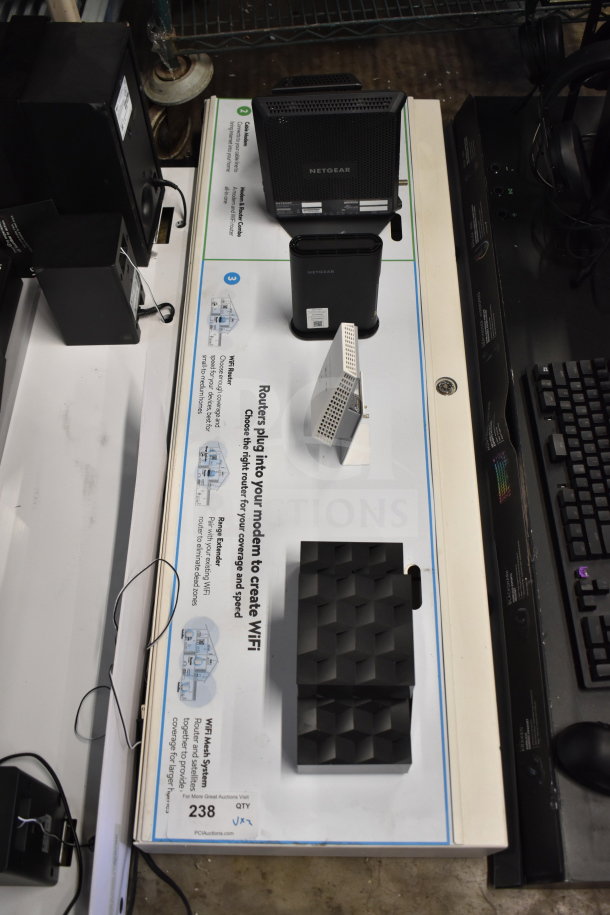 Auction item display with Netgear routers, headphones, and keyboard. Includes promotional materials and store setup.