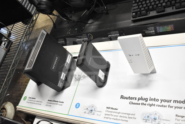 Netgear store display featuring headphones, keyboard, and two routers. Items are in good condition with visible brand logos and product labels.