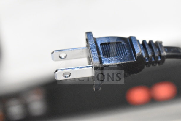 Two-prong power cord plug, close-up, associated with a Vizio/LG soundbar and speakers display set.