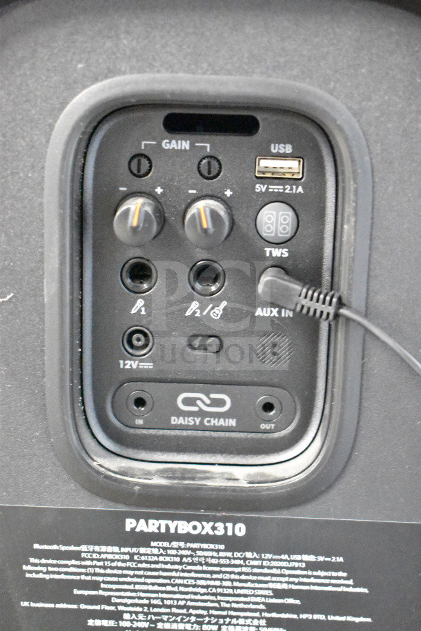 JBL Partybox 310 speaker panel with gain controls, USB port, AUX input, and daisy chain option. Model and details visible.