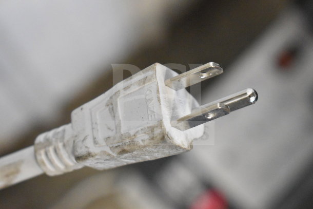 Close-up of a white, slightly dusty electrical plug. No branding or model visible.