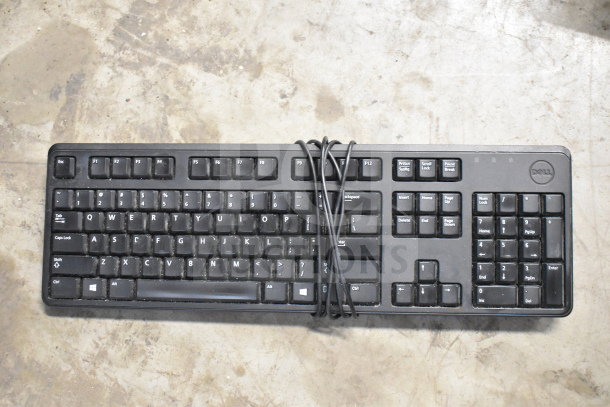 Dell corded office keyboard, black, showing signs of wear. Cord tied neatly. Model details not visible.