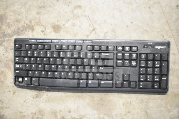 Logitech black keyboard with visible wear, includes function keys and numeric pad, part of an assorted office device lot.