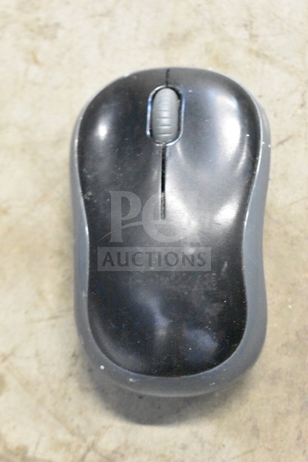 Black wireless computer mouse on a marble surface, showing signs of wear with visible scuff marks and a central scroll wheel.