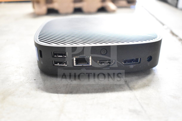 Compact computer dock with multiple ports including USB, Ethernet, HDMI displayed on a concrete surface.