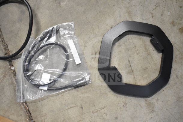 Black cable in packaging and hexagonal black frame on concrete floor. No visible computer mouse or keyboard.