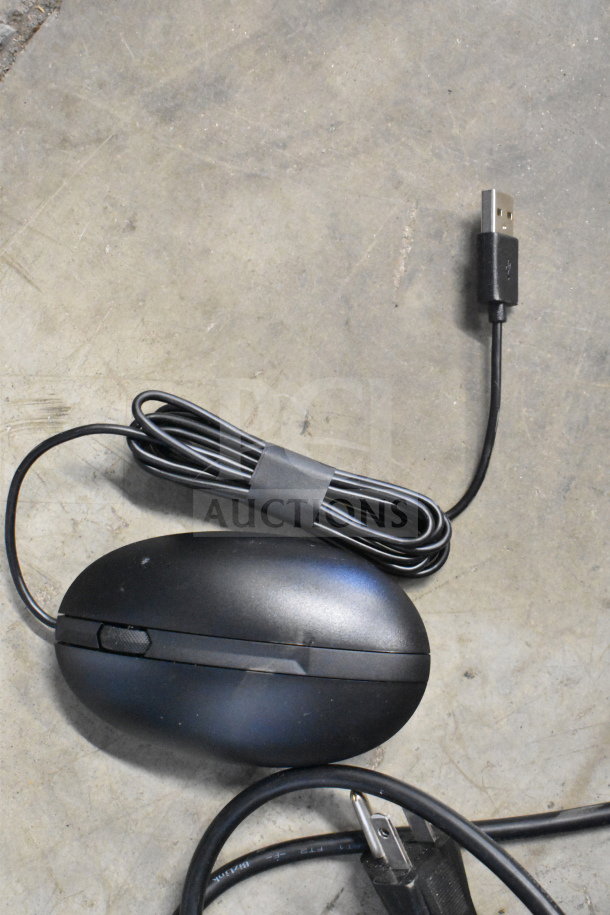 Black computer mouse with USB cable, textured scroll wheel, used condition, placed on a concrete surface.